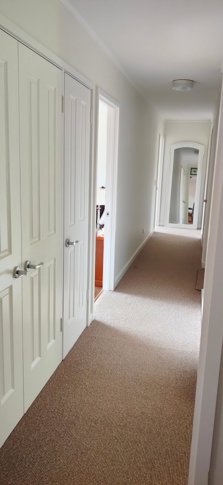 Long hallway with freshly painted white walls and doors